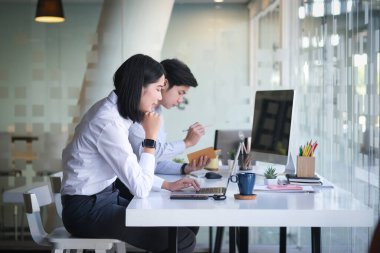 Resmi kıyafetler giyen iki iş adamı ofiste mali evrakları tartışıyor..