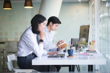 Resmi kıyafetler giyen iki iş adamı ofiste mali evrakları tartışıyor..