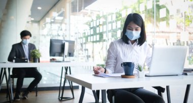 Resmi kıyafetler giyen iki iş adamı ofiste mali evrakları tartışıyor..