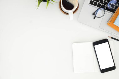 Not defteri, dizüstü bilgisayar ve kahve fincanı fare notlu üst görünüm ofis malzemeleri. Boş ekran cep telefonu ve masa başı çalışma alanı üzerindeki malzemeler ve kopyalama alanı..