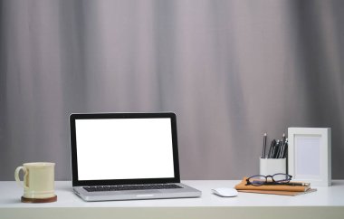 Boş ekranlı ve beyaz masadaki ekipmanlı modern çalışma alanı. Bilgi için boş ekran.