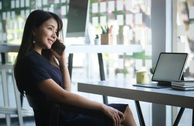 Side view of businesswoman using smartphone browsing and messaging with friends.	