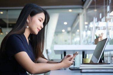 Side view of businesswoman using smartphone browsing and messaging with friends.	