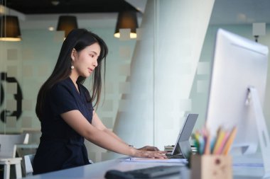 A businesswoman working on new project with laptop computer in modern office.	