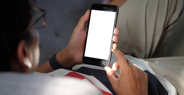 Mock up smartphone of hand holding black mobile phone with blank white screen.