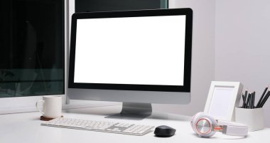 Boş ekranlı ve beyaz masadaki ekipmanlı modern çalışma alanı. Bilgi için boş ekran.