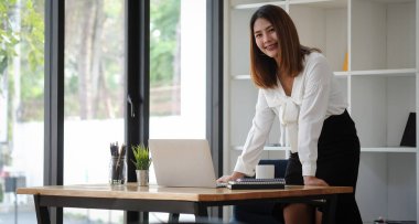 A young female administrative assistant making notes of working planning organizing information in her office.	