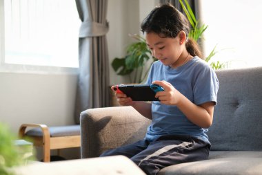 Cheerful young asian woman smiling and surfing internet on computer tablet in living room.	