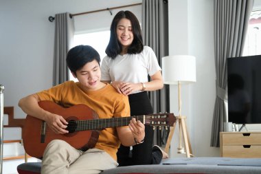 Mutlu genç çift oturma odasındaki kanepede rahatça oturuyor ve hafta sonları evdeki tablette internet gezintisi yapıyor.