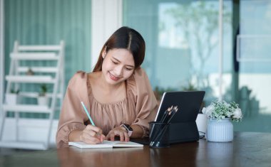 Business woman reading information on paperwork and using laptop working on desk.	