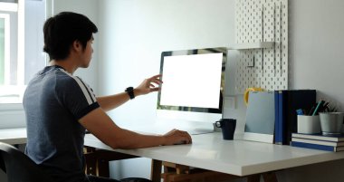 Evde bilgisayarla çalışan genç bir adamın arka plandaki görüntüsü.