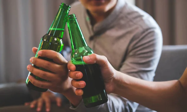 Happy Two Men Sitting Couch Clinking Bottles Beer Together — Zdjęcie stockowe