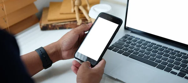 Mock up smartphone of hand holding black mobile phone with blank white screen.