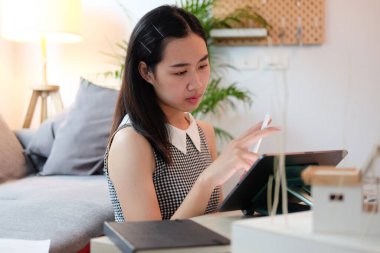 Evde taslak ve bilgisayar tabletleriyle çalışan kadın mimar.