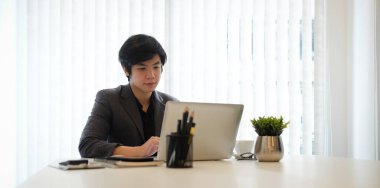 İş adamı modern işyerinde oturuyor ve bilgisayar laptopuyla çalışıyor..