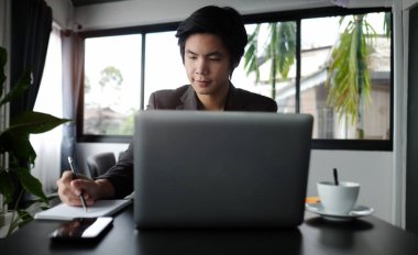 Genç girişimci odasında dizüstü bilgisayarla çalışıyor..