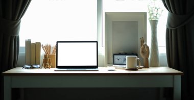 Bilgisayarı, resim çerçevesi ve ahşap masadaki kitapları olan rahat bir iş yeri..