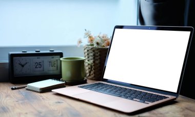 Bilgisayar dizüstü bilgisayar, kahve fincanı, defter ve ev bitkisi ahşap masada..