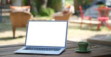 Laptop bilgisayarı ve kahve fincanını açık kafedeki ahşap masaya koyun..