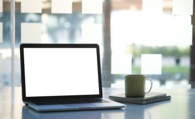 Bilgisayar laptopu ve kahve fincanı beyaz ofis masasında..