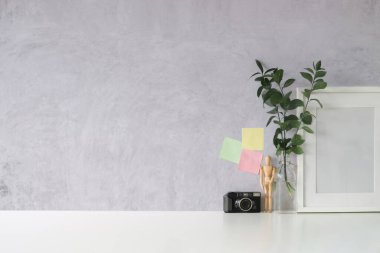 Boş çerçeve, ev bitkisi ve kamera beyaz masada.