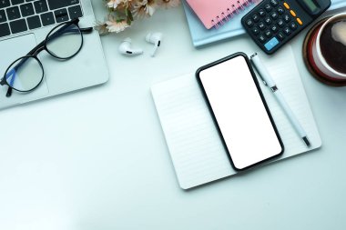 Cep telefonunu, defterini, laptopunu ve kahve fincanını beyaz masaya koy..