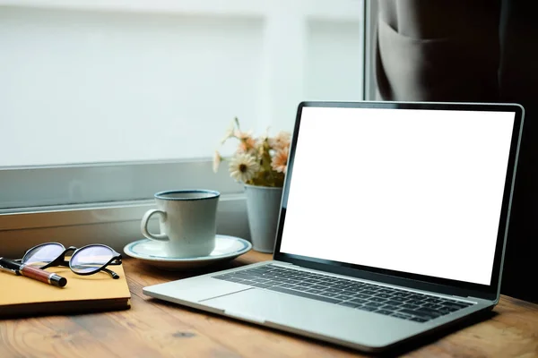 Laptop computer, glasses and coffee cup on wooden desk.