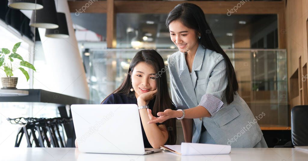 Two business women discussing business data with computer laptop at modern office.