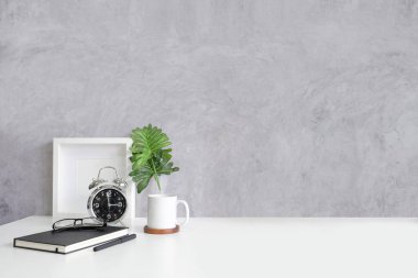 Boş çerçeve, kahve fincanı ve kalem tutacağı ahşap masa ve tuğla duvarlı.