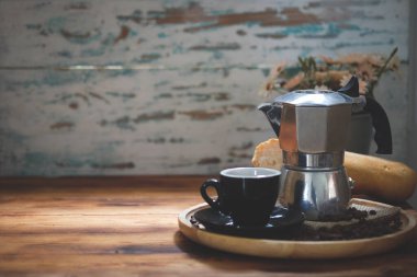 Kahve fincanı ve kahve makinası ahşap masada..