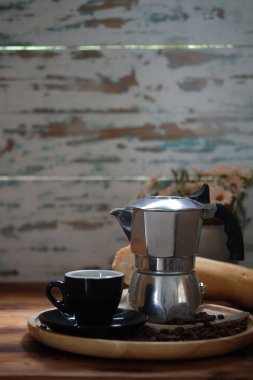 Kahve makinası ve kahve fincanı ahşap masada..
