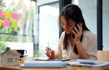 Business woman reading information on paperwork and using laptop working on desk.	