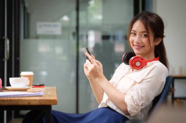 Cep telefonu tutan ve kameraya gülümseyen kadın..