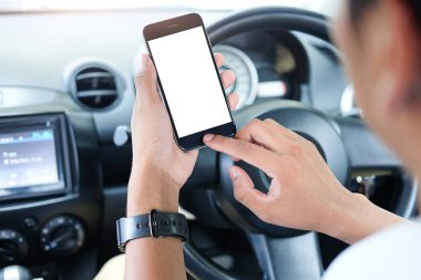 Kesilmiş görüntü. Şoför araba kullanırken telefonu kullanıyor. Yuvarlak kenarlı modern akıllı telefon. Model için izole ekran. Arka planda araba navigasyon görüntüsü. 