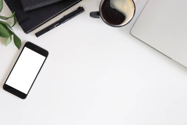Not defteri, dizüstü bilgisayar ve kahve fincanı fare notlu üst görünüm ofis malzemeleri. Boş ekran cep telefonu ve beyaz masa çalışma alanı üzerindeki malzemeler ve kopyalama alanı..