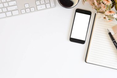 Not defteri, dizüstü bilgisayar ve kahve fincanı fare notlu üst görünüm ofis malzemeleri. Boş ekran cep telefonu ve beyaz masa çalışma alanı üzerindeki malzemeler ve kopyalama alanı..