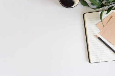 Not defteri, dizüstü bilgisayar ve kahve fincanı fare notlu üst görünüm ofis malzemeleri. Boş ekran cep telefonu ve beyaz masa çalışma alanı üzerindeki malzemeler ve kopyalama alanı..