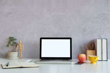 Bilgisayar laptopunu, kitapları, kahve fincanını ve çimento duvarlı beyaz masa bitkisini taklit et..