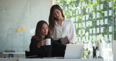 İki iş arkadaşı modern işyerinde projelerini tartışıyor..