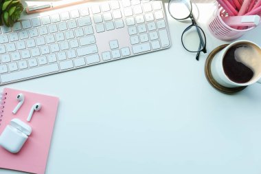 Kahve fincanı, kalem tutacağı ve beyaz masadaki not defteriyle kadın çalışma alanı.