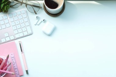 Kahve fincanı, gözlük, kulaklık ve defterle üst düzey kadın çalışma alanı.