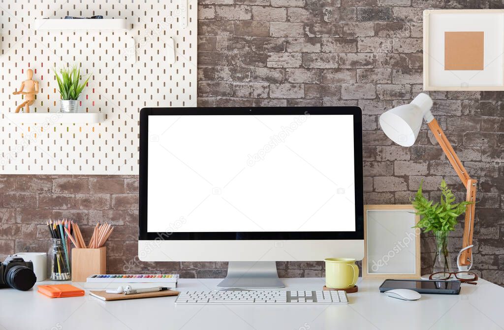 Front view computer with blank screen on white table with brick wall.