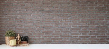 Kamera, kahve fincanı ve beyaz masada tuğla duvarlı kitaplar olan şık bir çalışma alanı. Ürün görüntüleme kurgusu için alanı kopyala.