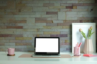 Stylish workspace with computer, coffee cup and picture frame on white table.	