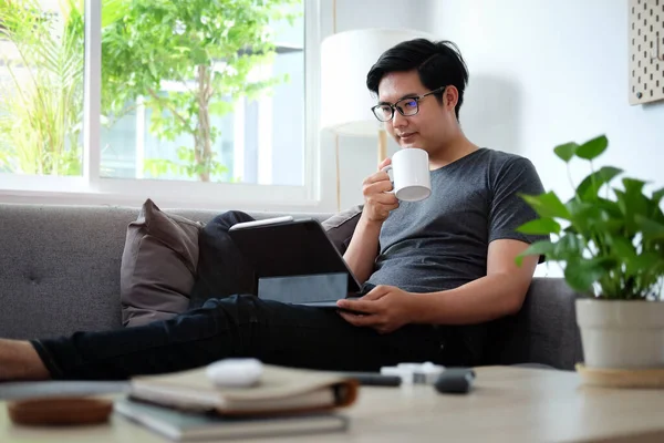 Genç Asyalı Adam Rahat Koltukta Oturuyor Dijital Tablet Kullanıyor — Stok fotoğraf