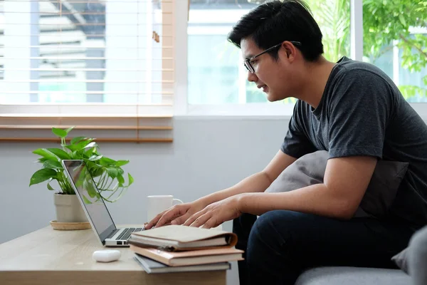 Kanepede Oturan Asyalı Adam Dizüstü Bilgisayar Kullanıyor — Stok fotoğraf