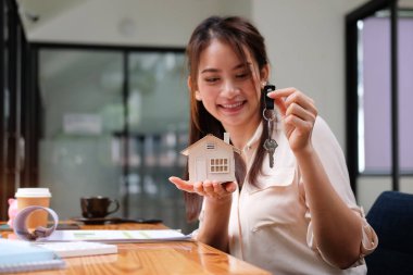 Evin modelini ve anahtarını elinde tutan kadın. Gayrimenkul ve mortgage yatırım kavramı.