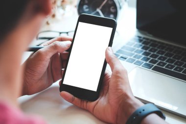 Bilgisayarın başında oturan ve akıllı telefon kullanan adamın üstünden bak..