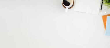 Üst düzey kahve fincanı, ev bitkisi ve beyaz masadaki boş defter. Boşluğu kopyala.