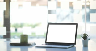 Modern ofisteki beyaz masaya boş ekran ve kahve fincanı ile bilgisayar laptopunu taklit et.